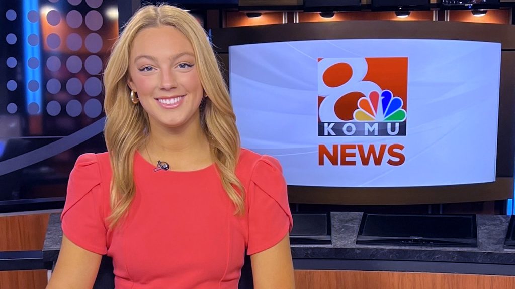 Charlotte Cicero sitting at a news desk in front of a screen displaying the KOMU logo